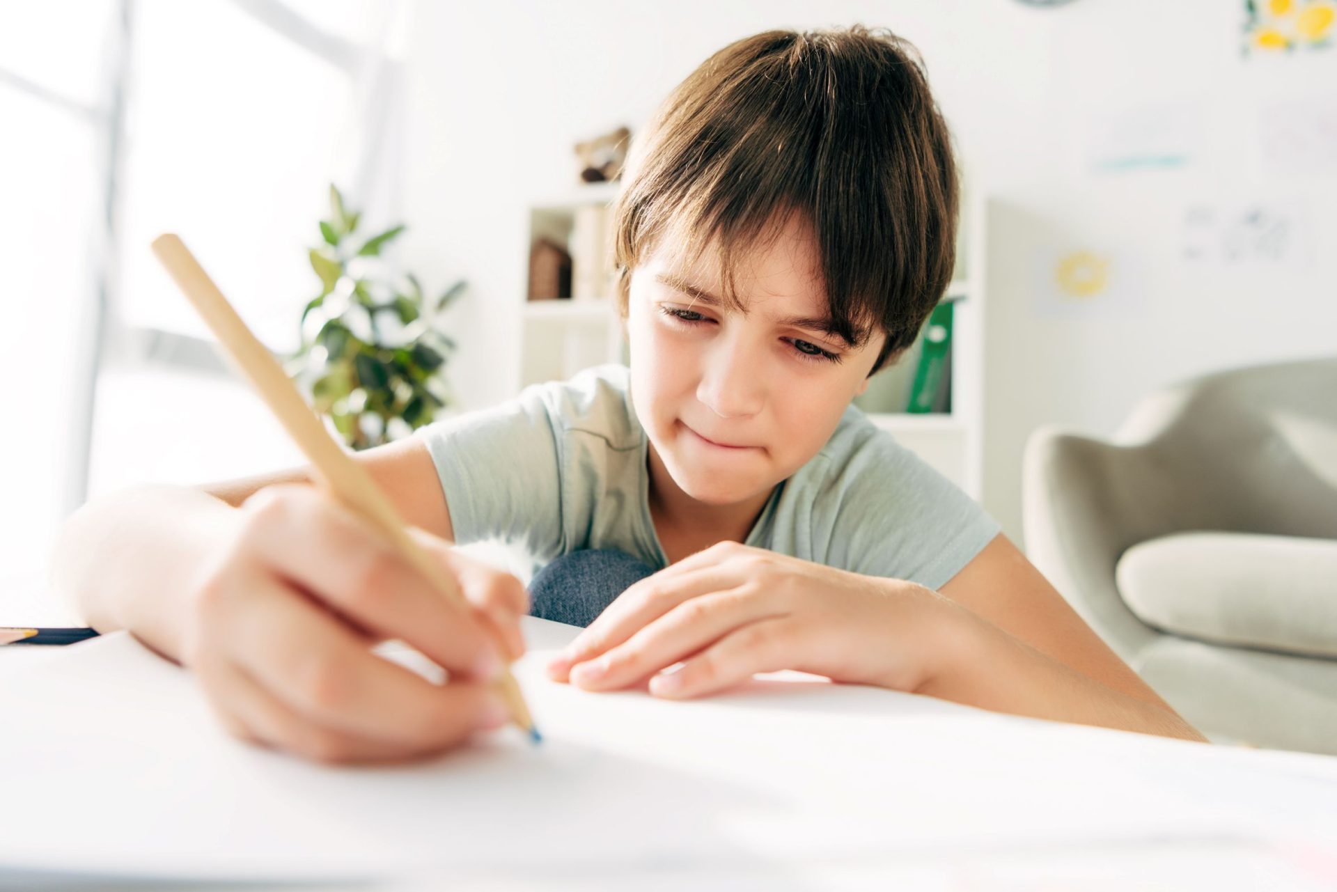 kid with dyslexia drawing with pencil and sitting